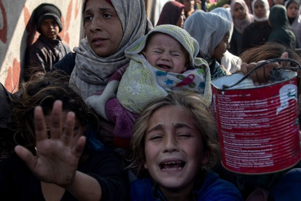 Palestinianos, incluindo crianças, seguram tachos e panelas de metal enquanto se reúnem para receber alimentos cozinhados por uma cozinha de beneficência, em Khan Yunis, no sul da Faixa de Gaza. De acordo com a agência das Nações Unidas para os refugiados palestinianos, mais de 1,8 milhões de pessoas na Faixa de Gaza sofrem de «elevados níveis» de insegurança alimentar aguda, com uma desnutrição aguda dez vezes superior à que se verificava antes da guerra. 10 de janeiro de 2025