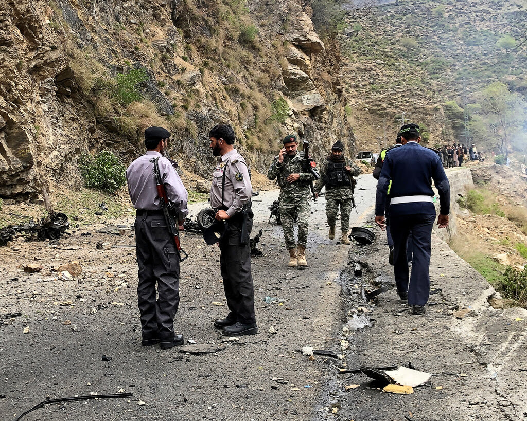 Men in uniform inspect a charred road.