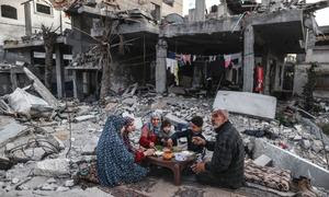 Una familia en Gaza come en las ruinas de la que fue su casa.