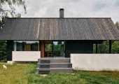 La estructura principal es un volumen cuboidal con un tejado a dos aguas, ambos revestidos de madera oscura teñida, inspirada en las estructuras agrícolas tradicionales de la zona.