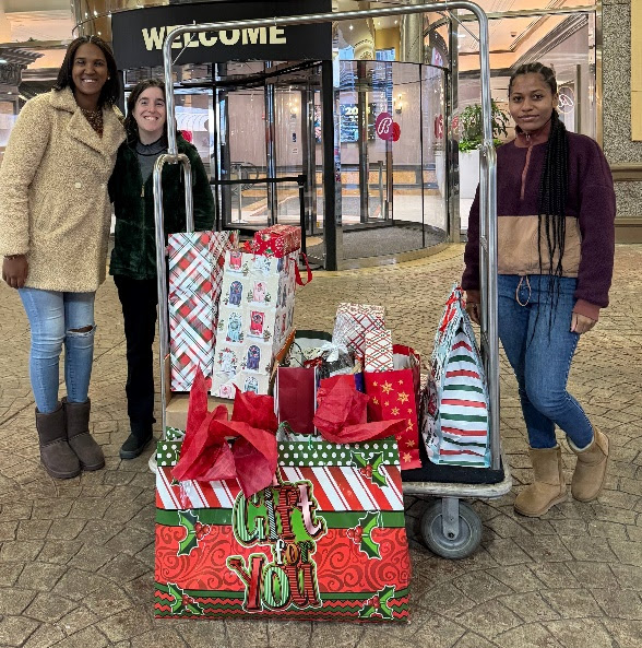 A group of women standing next to a cart with presentsDescription automatically generated