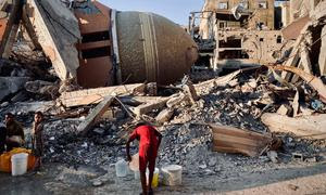 Una persona colecta agua entre las ruinas en Gaza.