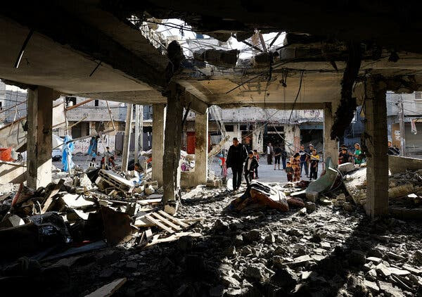 People can be seen in the street outside a gutted building in Rafah, in southern Gaza. A man and a boy are entering the building.