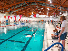 Image of pool with underwater robot and people looking in the pool