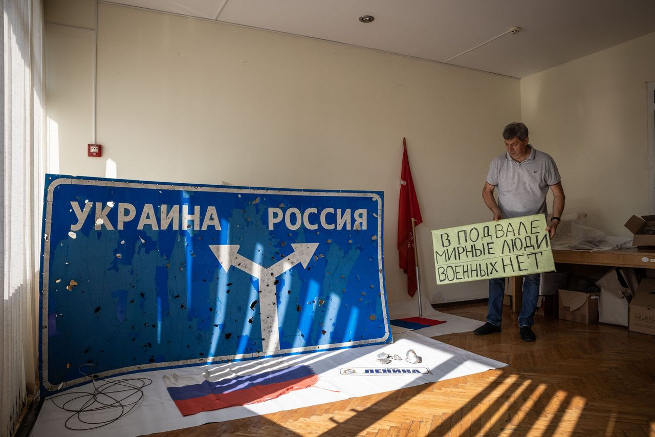 Yuriy Savchuk holds a sign reading “There are civilians in the basement, there are no military” next to other items taken from Ukraine’s invasion of Russia Kursk Region, in Ukraine’s war Museum in Kyiv. (Ed Ram/For The Washington Post)