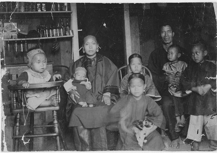 A black and white photograph of a man and woman posing formally with children in a kitchen.