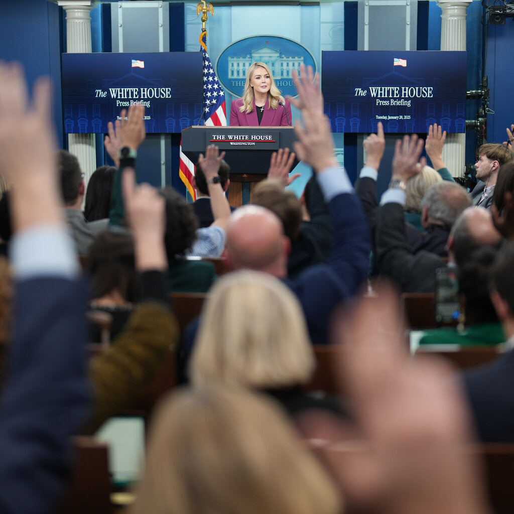 Karoline Leavitt standing behind a lectern in the White House press room. 