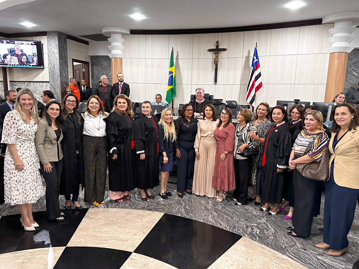 Grupo de magistradas, em pé lado a lado, no salao do Pleno do TJMA. Ao centro, a desembargadora Maria do Socorro Carneiro vestindo calça e blazer beges