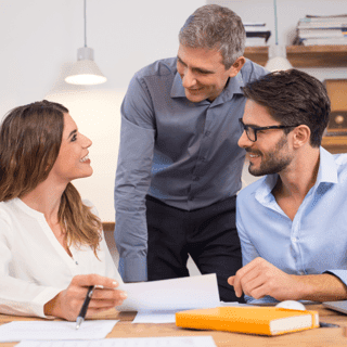 Manager speaking to two team members while working on project.