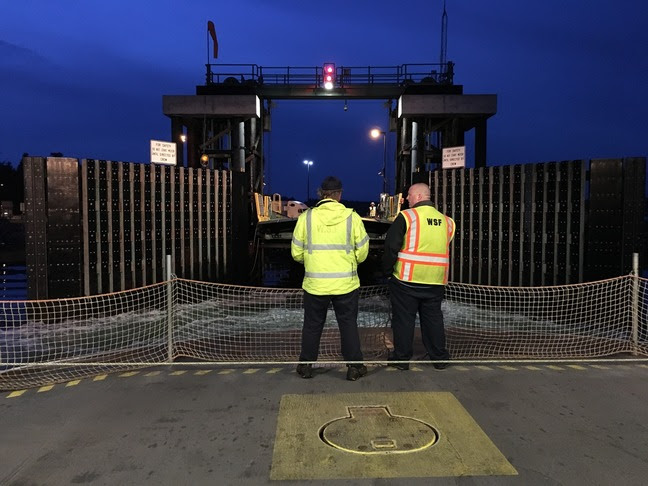 Two ferry crew members on the car deck as the vessel approaches Coupeville terminal at night