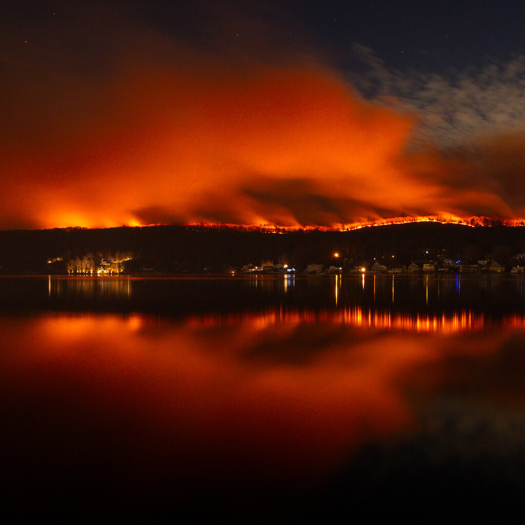 A fire burning above a lake.