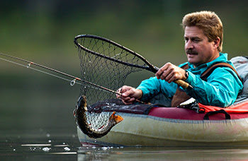 An angler in a float tube nets a brook trout on a lake in Luce County.