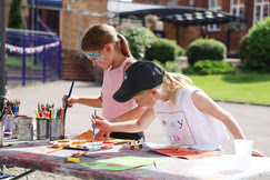 two young girls are painting outside at a stall