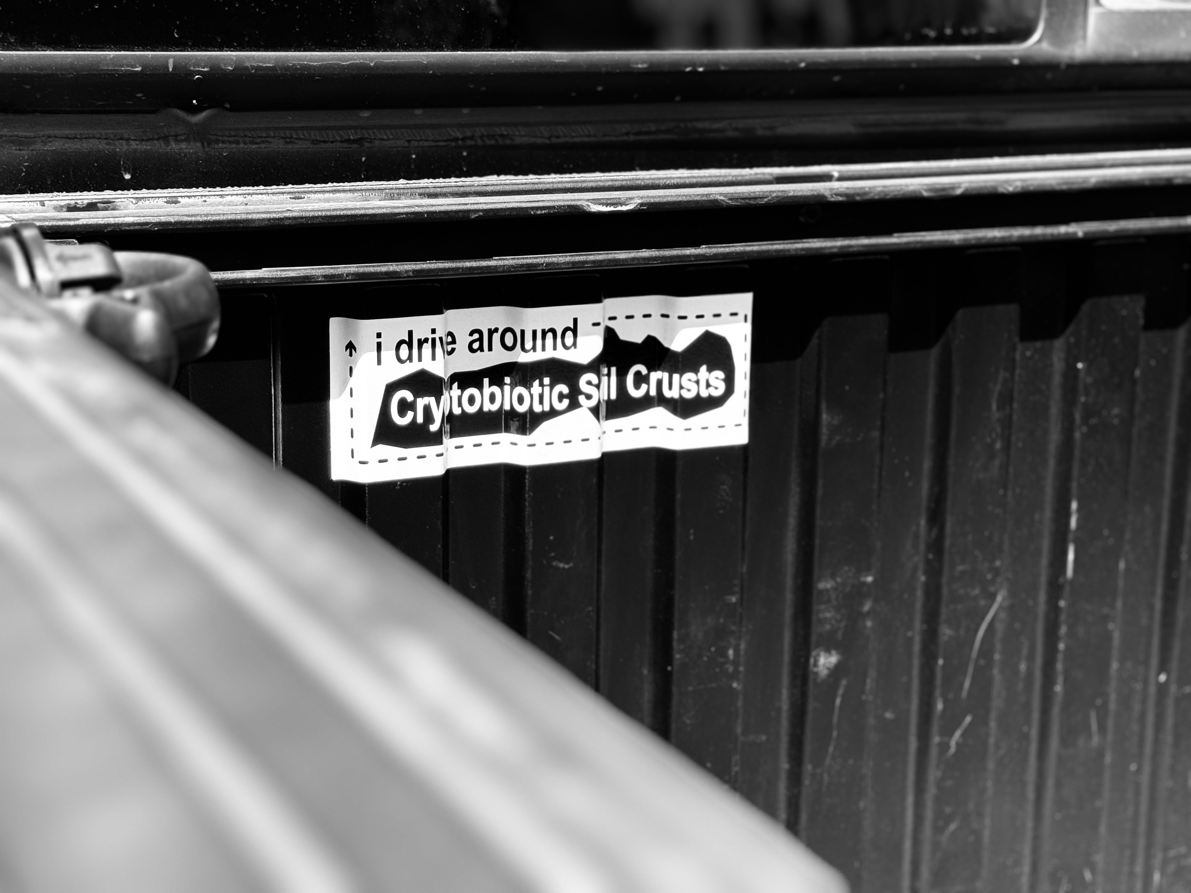 hey mitch this is an i drive around cryptobiotic soil crusts bumper sticker in a tacoma bed