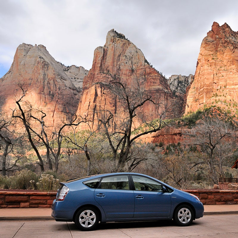 A parked blue Toyota Prius, with scenery of Utah in the background.