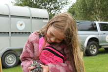 a young girl is holding a chicken, she is looking down at it, smiling