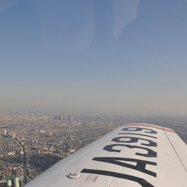 The wing of an airplane with bold lettering on it over a cityscape.