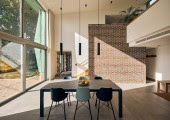 El corazón de la casa es un espacio a doble altura conectando visualmente el salón y la cocina de planta abierta con un altillo diseñado como espacio de trabajo.