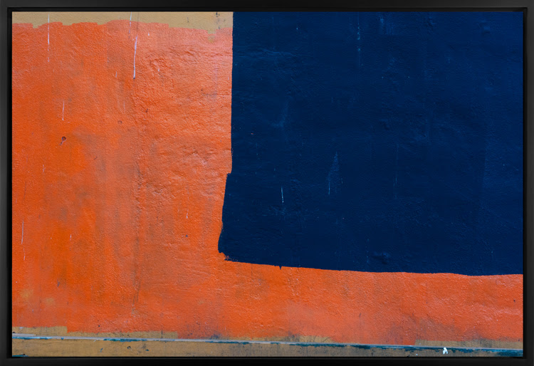 Color image of a large photograph of a wooden exterior wall with red and blue paint splotches covering its surface 