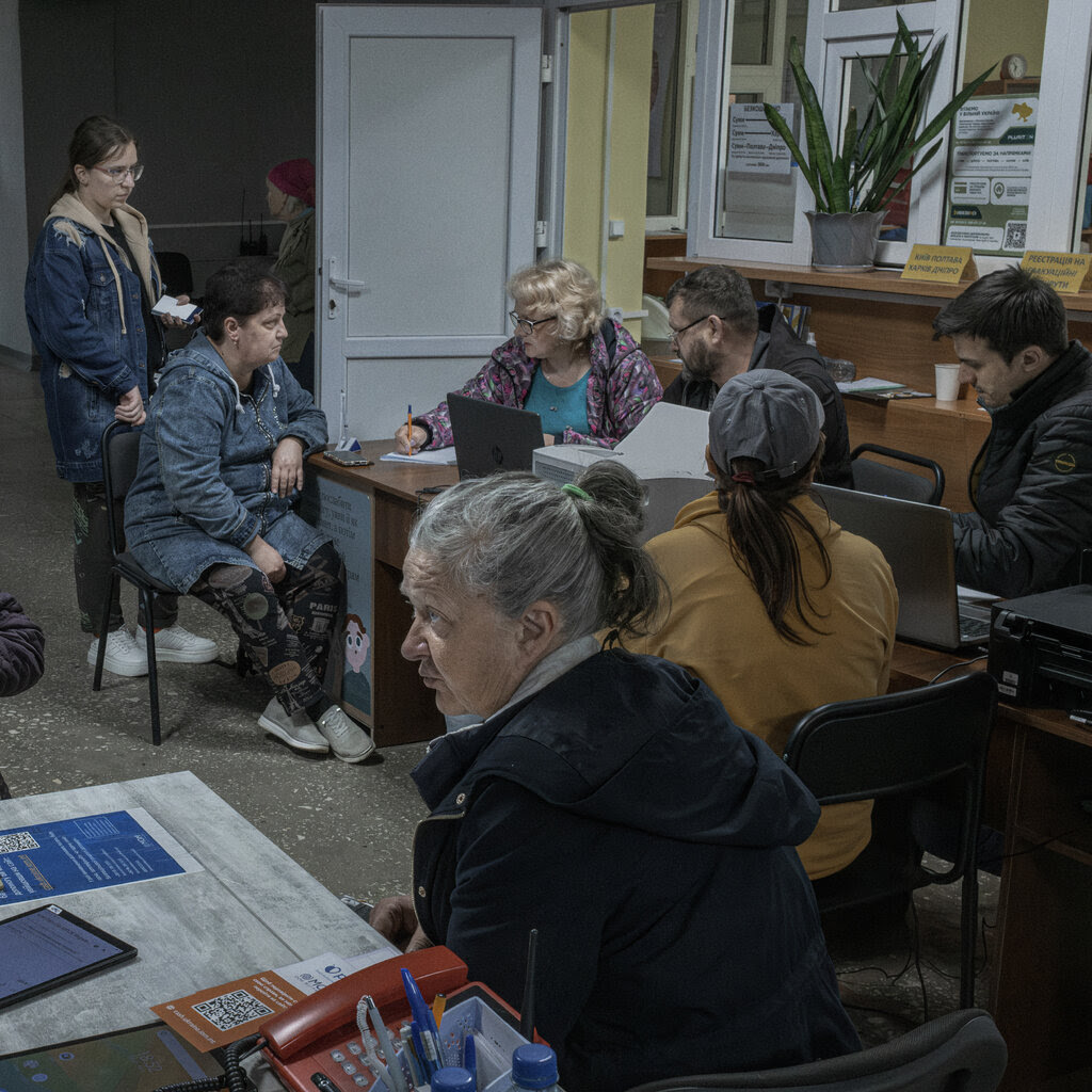 A group of people in a room registering with workers at desks.