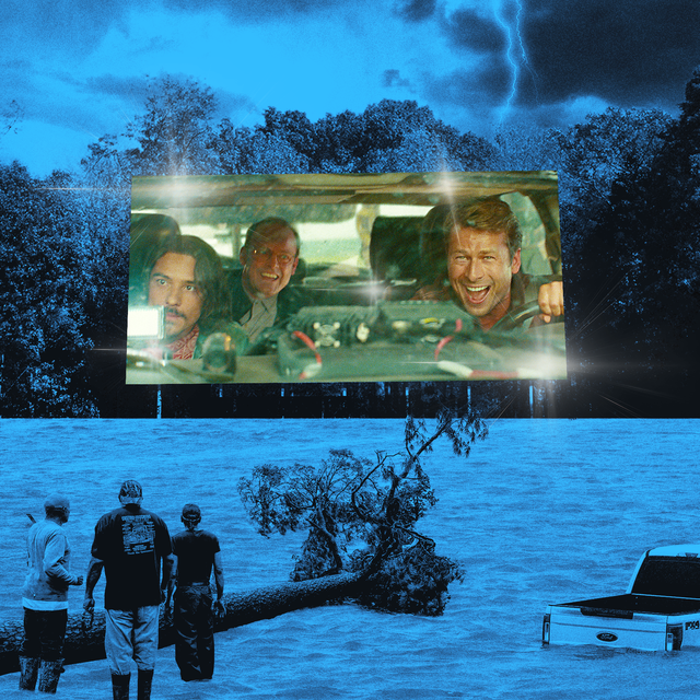 A movie screen outdoors shows a scene from “Twisters,” and people watch while standing in floodwaters.