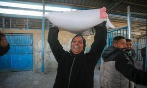 Una mujer lleva harina distribuida por UNRWA en Gaza.