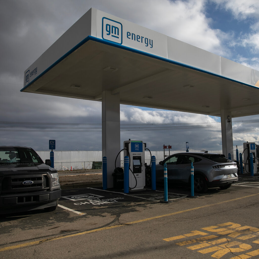 Two cars parked by an electric vehicle charging station. 