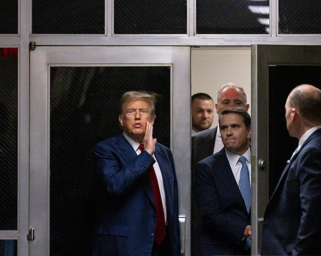 Donald Trump raises his hand to his face outside a courtroom in New York. 
