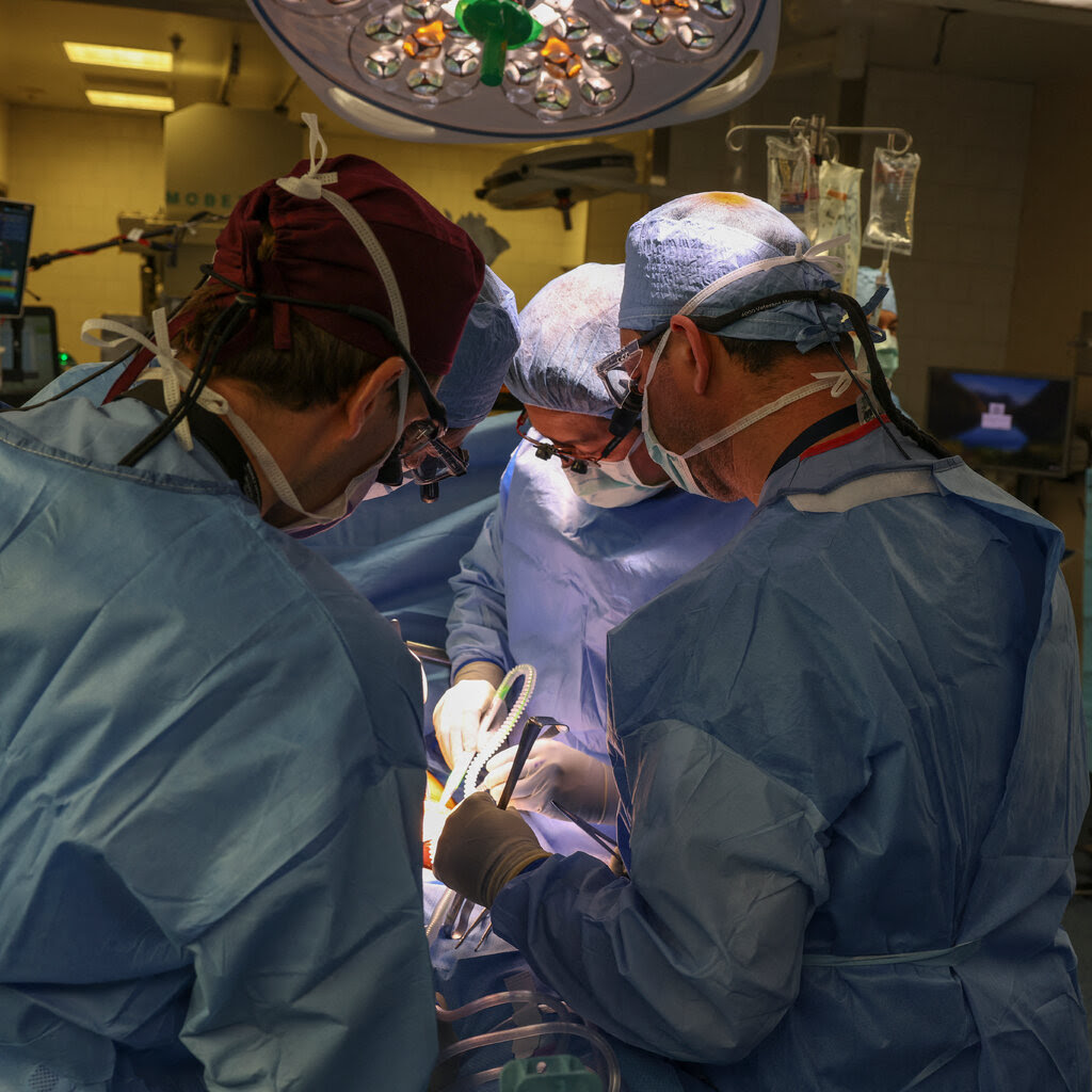 Surgeons hunch over a patient during an operation.
