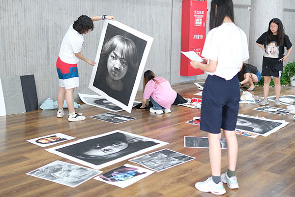 Students hanging artwork at an exhibition.