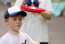 a young boy balances a plate on a stick, he is concentrating on doing this