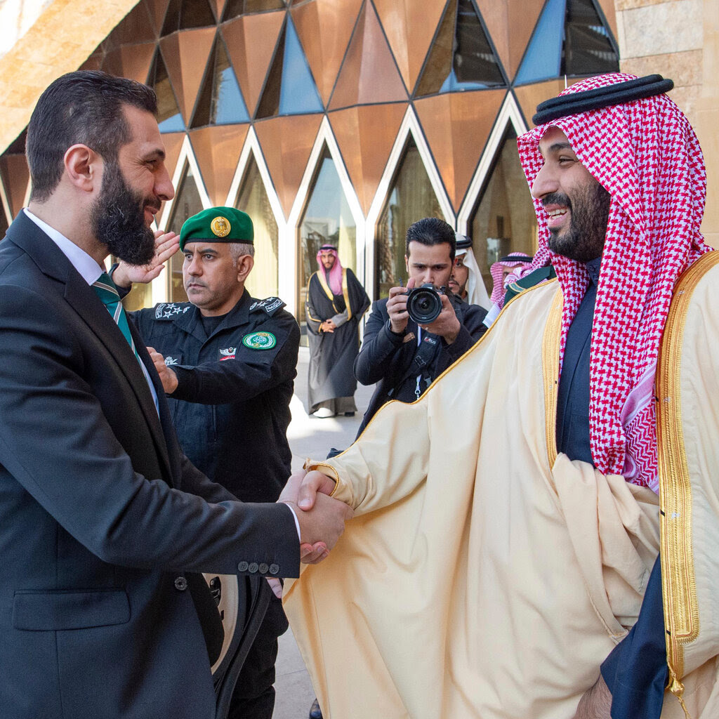 Crown Prince Mohammed bin Salman, right, shakes hands with Ahmed al-Shara.