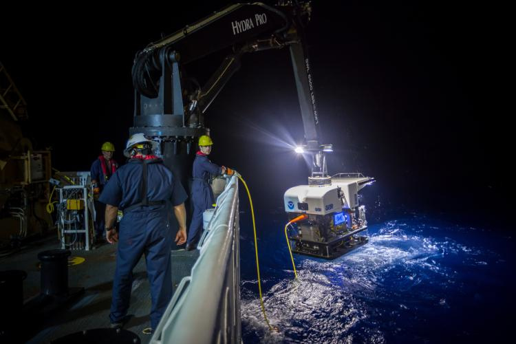 Remotely operated vehicle being brought aboard NOAA Ship Okeanos Explorer at night by crew members