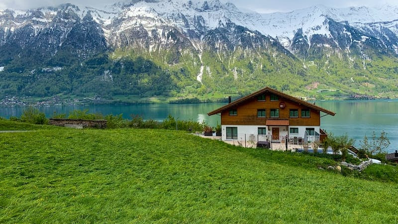 white and brown house near green grass field and mountain during daytime