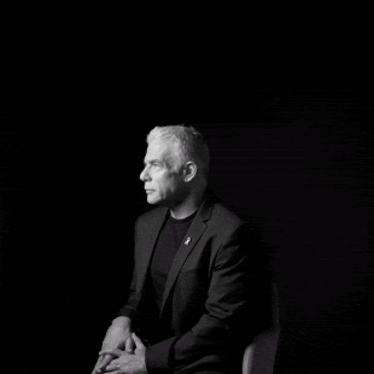 An animated black-and-white GIF of a white man with white hair in a chair turning to the camera.
