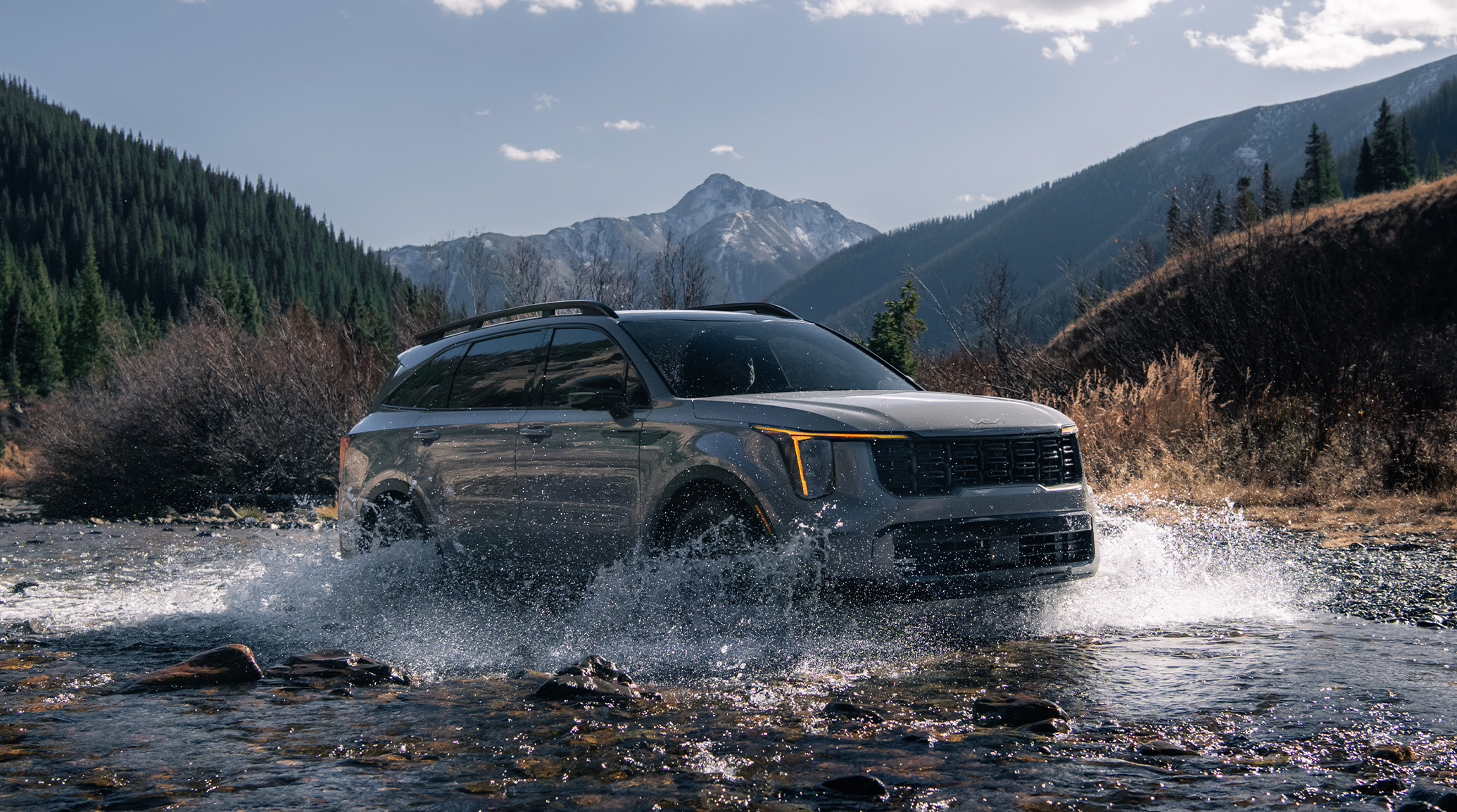 2024 Kia Sorento in brown, three-quarter front view, driving through a river of water in the mountains