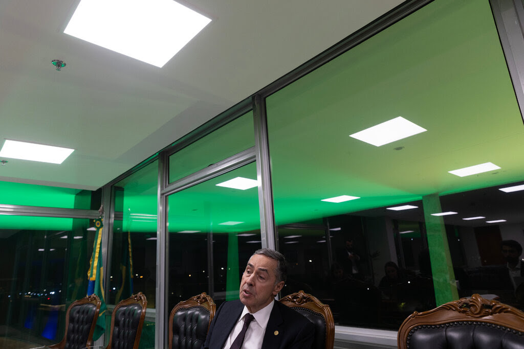 Luís Roberto Barroso sits in a chair in a glass-walled room. 