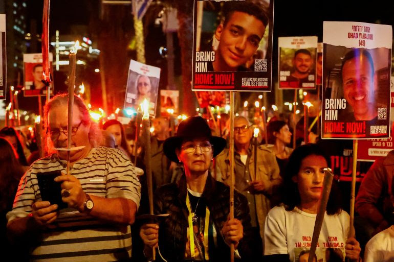 People hold candles and signs with photos of Israeli hostages, who are being held in the Gaza Strip after they were seized by Hamas gunmen on October 7, as the country observes the Jewish festival Hanukkah amid the ongoing conflict between Israel and the Palestinian Islamist group Hamas, in Tel Aviv, Israel December 7, 2023. REUTERS/Clodagh Kilcoyne