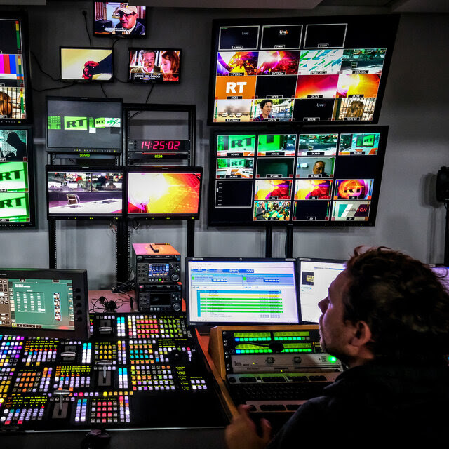 Screens with images in red, green and orange and a man and a woman sitting in front of them.