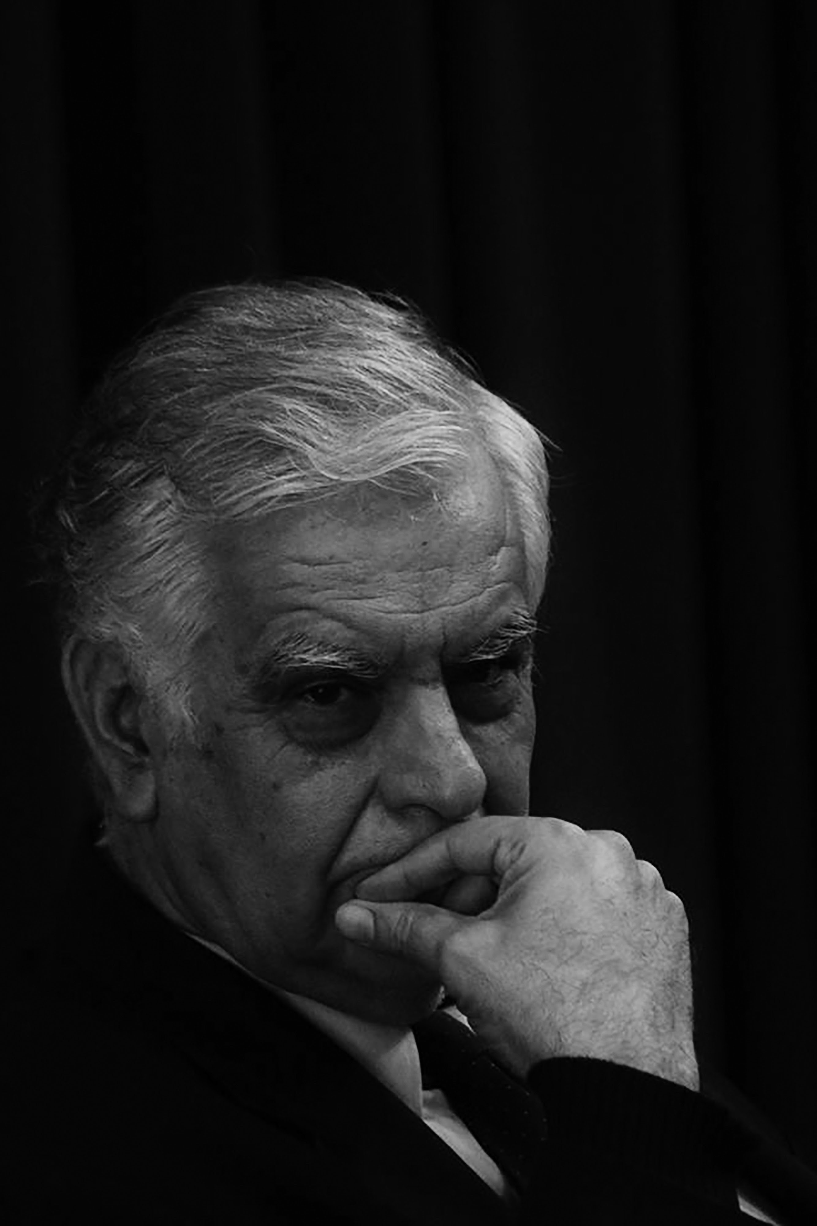 Alfaguara publica 'Palabras en el mundo' de Alonso Cueto, un retrato revelador de Mario Vargas Llosa Retrato en blanco y negro de un hombre mayor con cabello canoso y barba, pensativo, con una mano tapando parte de su boca.