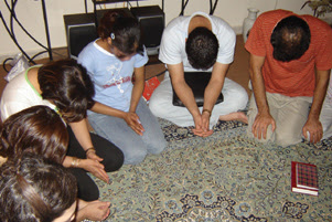 A small group of Christians is on their knees, heads bowed in prayer.