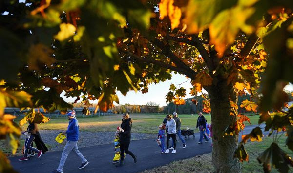 Parents and children leave after receiving free Halloween candy from a local businessman, Tuesday, Oct. 31, 2023, in Lewiston, Maine. Locals seek a return to normalcy after a shooting that claimed 18 lives in their community on Oct. 25. (AP Photo/Matt York)