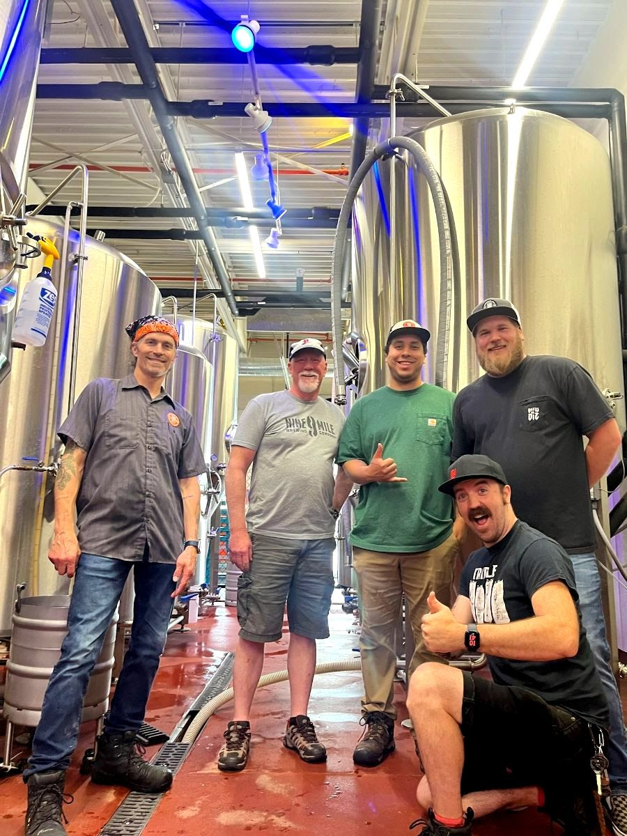 Photograph of brewing team members from 9 Mile and Wooden Hill, smiling with brewing equipment in the background.