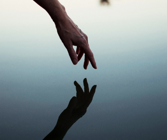 Hand touching it's reflection in water