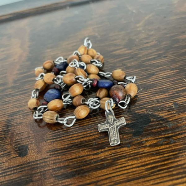 A strand of brown and blue prayer beads with a cross on a wooden background