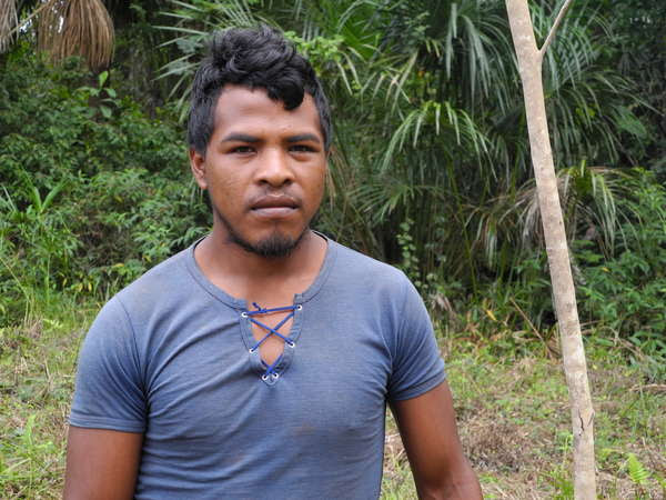 Paulo Paulino Guajajara in a blue t-shirt with the forest behind him.