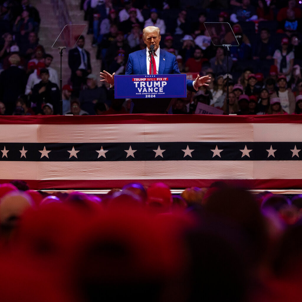 Donald Trump, hands extended, gives a speech behind a lectern. 