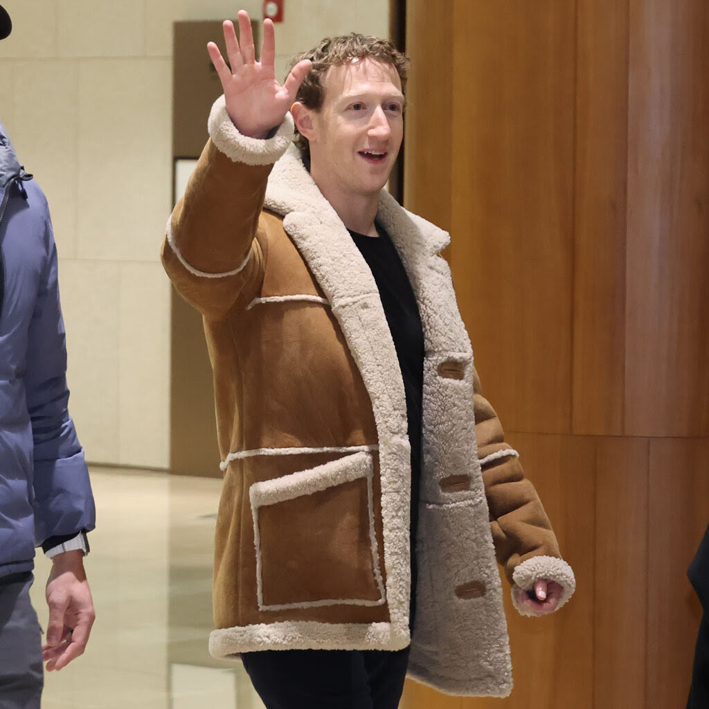 Mark Zuckerberg wearing a tan shearling jacket and waving. 