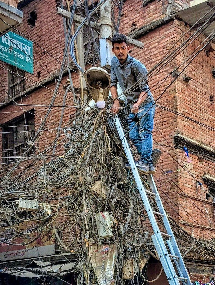 Another man up telephone pole amongst tons of wires.