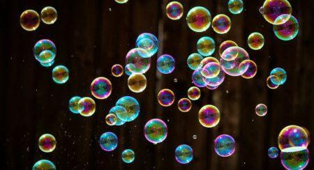 Numerous spherical soap bubbles in front of a dark background